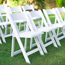 Load image into Gallery viewer, Silla plegable de resina blanca con asiento acolchado en un parque